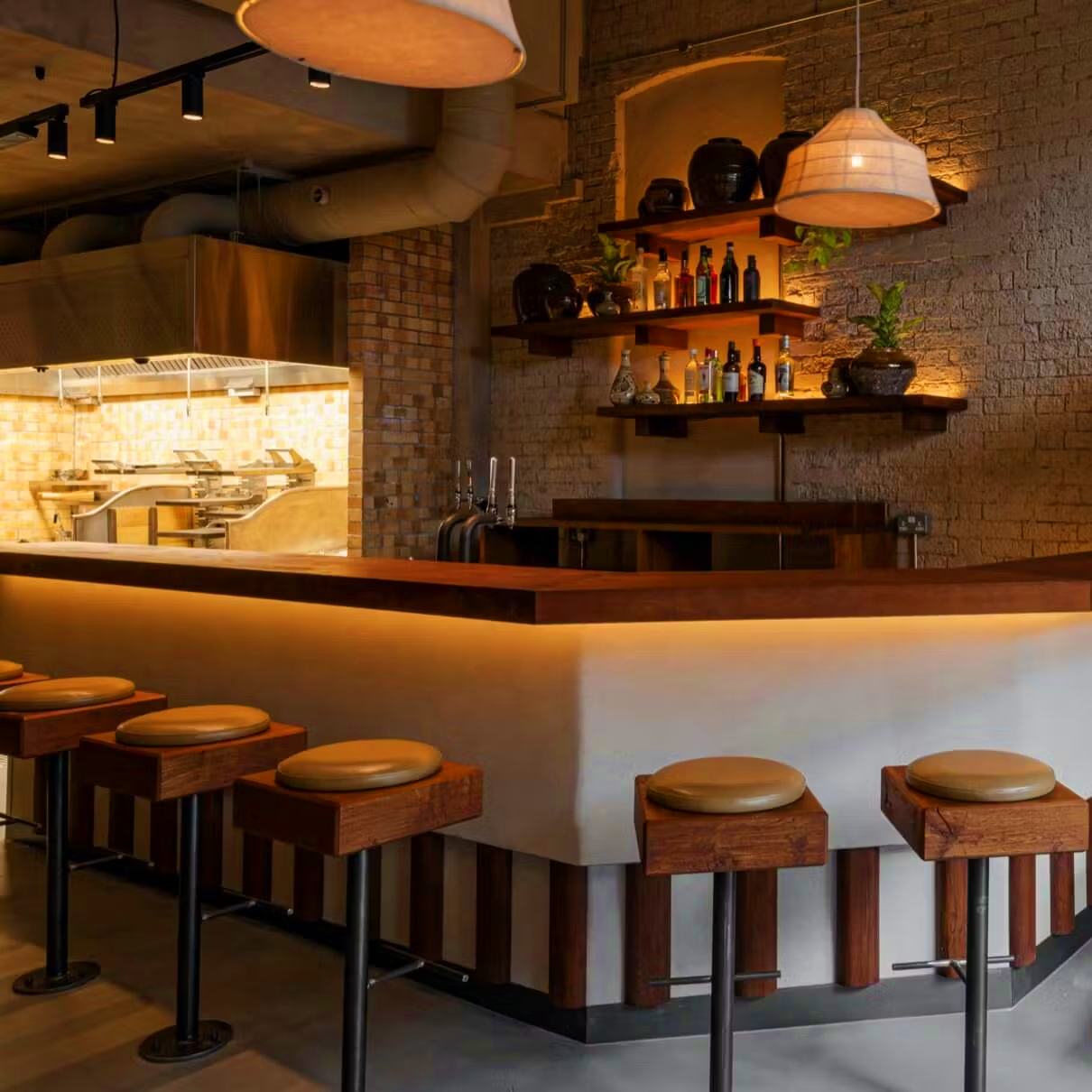 Bar area with wooden stools and a well-stocked bar in a cozy setting.