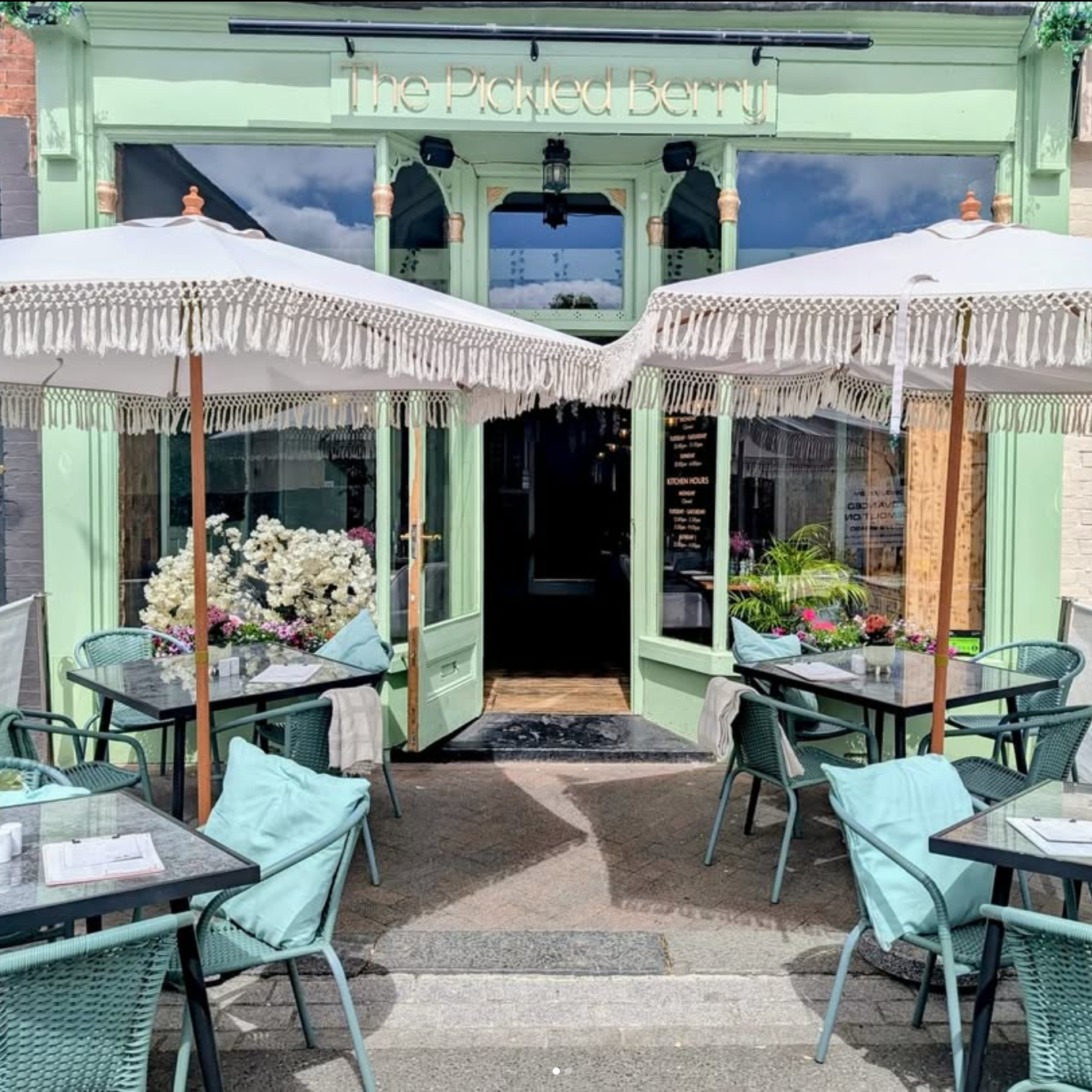 Outdoor seating area with tables, chairs, and umbrellas in front of a building named 'The Pickled Beet'.